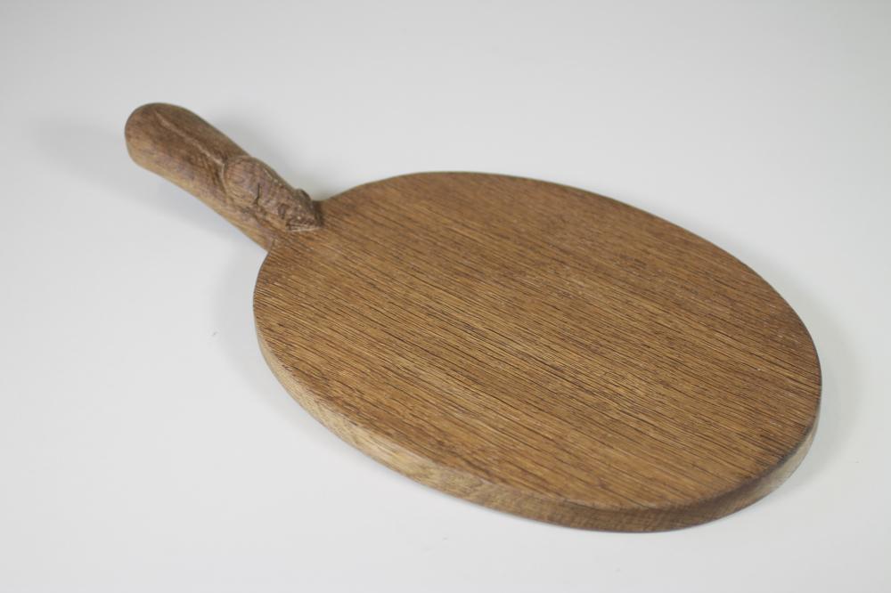 AN OAK CHEESE BOARD by Robert Thompson of plain oval form with carved mouse trademark to handle Image