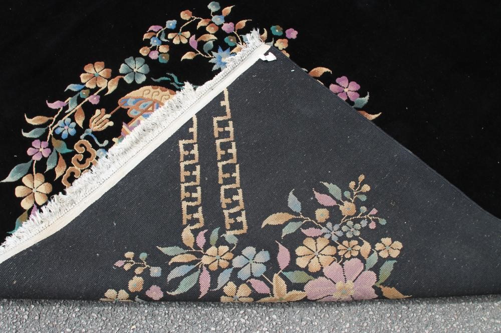 A CHINESE WASHED AND FRINGED BLACK GROUND CARPET with central polychrome floral spray and similar Image