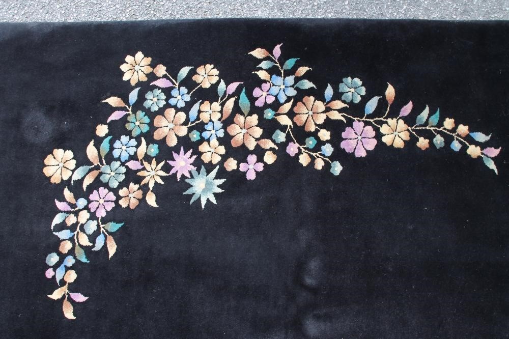 A CHINESE WASHED AND FRINGED BLACK GROUND CARPET with central polychrome floral spray and similar Image