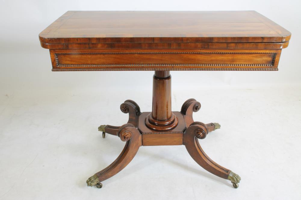 A REGENCY MAHOGANY FOLDING CARD TABLE of rounded oblong form with stringing and beaded edging Image