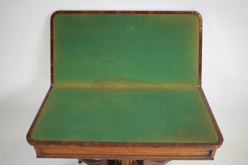 A REGENCY MAHOGANY FOLDING CARD TABLE of rounded oblong form with stringing and beaded edging Image