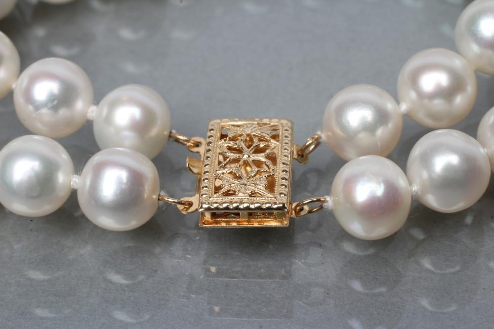 A TWO ROW CULTURED PEARL BRACELET with two fixed spacers between and foliate pierced clasp Image