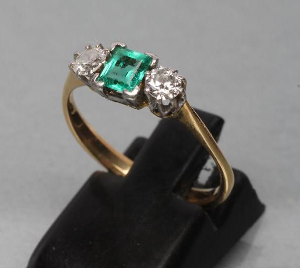 AN EMERALD AND DIAMOND THREE STONE RING Image
