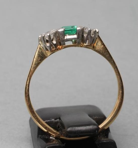 AN EMERALD AND DIAMOND THREE STONE RING Image