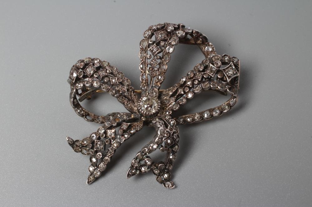 A VICTORIAN DIAMOND BOW BROOCH centred by an old cut stone of approximately 0.4cts and multi stone Image
