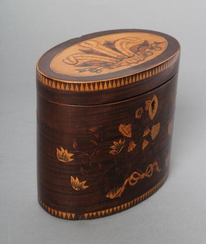 A REGENCY MAHOGANY TEA CADDY of oval form with ribbon tied marquetry flowers and berried branches Image