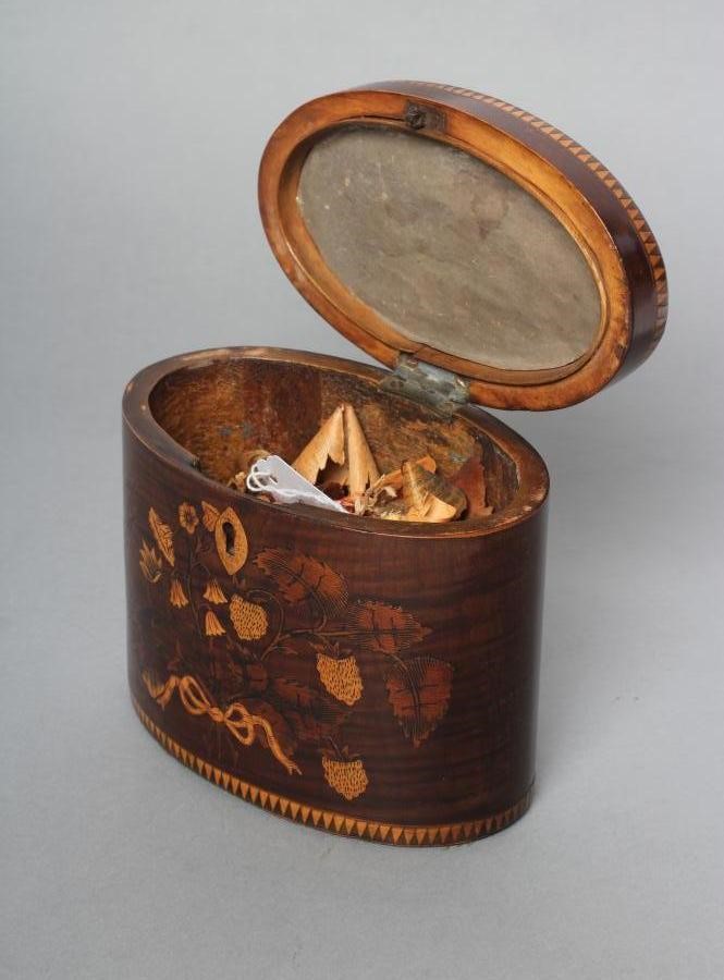 A REGENCY MAHOGANY TEA CADDY of oval form with ribbon tied marquetry flowers and berried branches Image