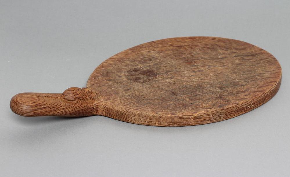 A ROBERT THOMPSON OAK CHEESE BOARD of oval form with carved mouse trademark in high relief to the Image