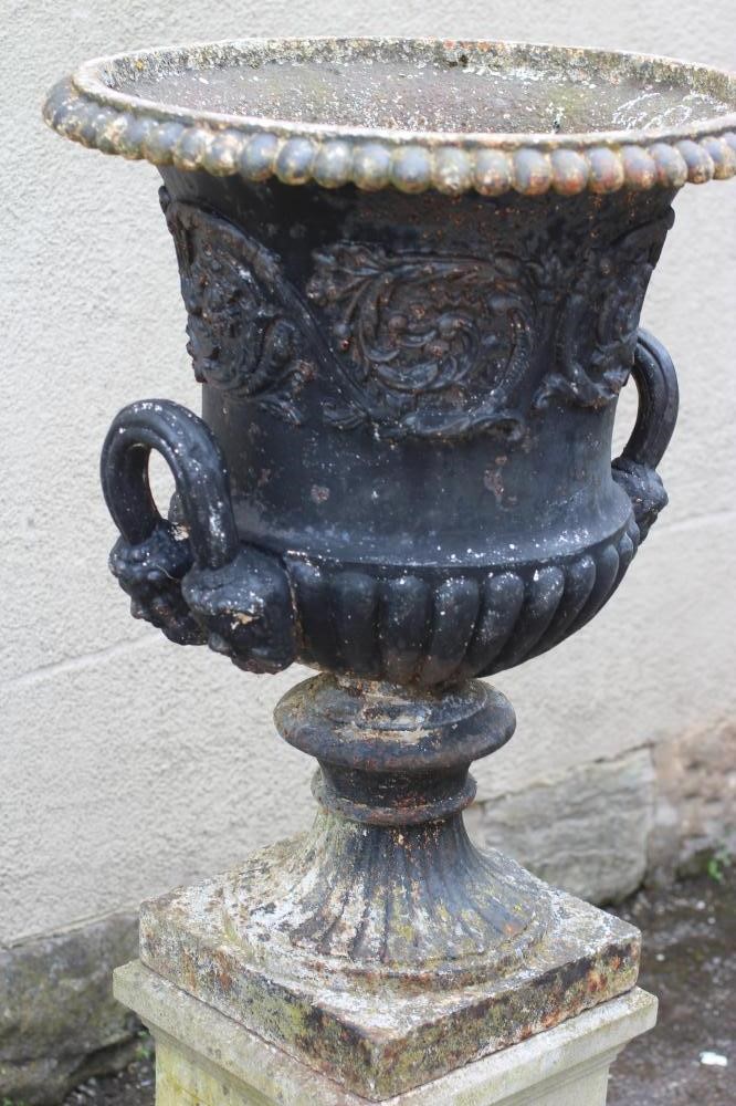 A VICTORIAN CAST IRON URN of half fluted form with mask headed loop handles Image