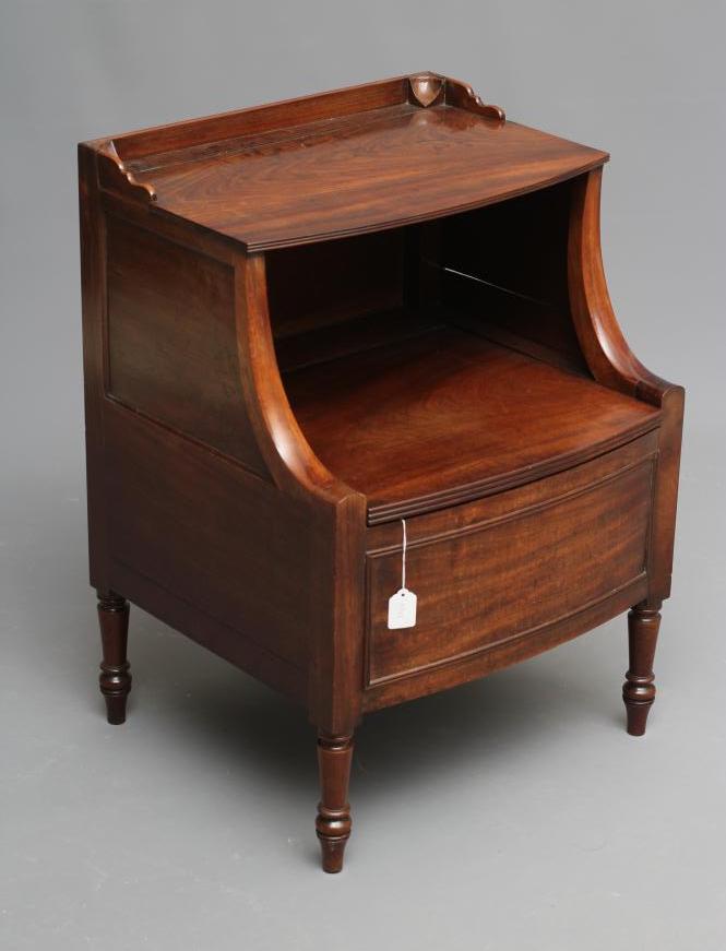 A regency mahogany "lancashire" commode of bowed form with hinged galleried top on shaped