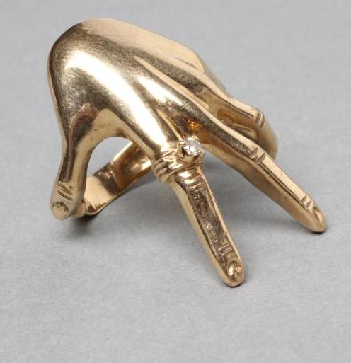 A 9CT GOLD COCKTAIL RING shaped as a lady's left hand wearing a diamond solitaire "ring" Image