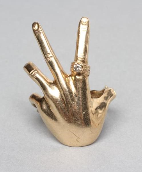 A 9CT GOLD COCKTAIL RING shaped as a lady's left hand wearing a diamond solitaire "ring" Image