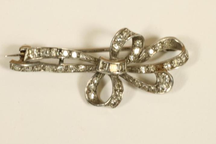 AN ART DECO DIAMOND BOW BROOCH pave set with brilliant and square cut stones to an unmarked white Image