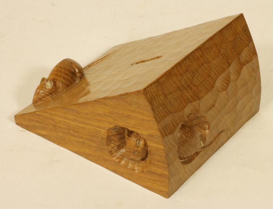 AN ADZED OAK MONEY BOX by Robert "Mouseman" Thompson modelled as a wedge of cheese with two carved Image