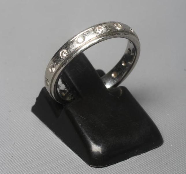 A PLATINUM ETERNITY RING with small diamonds in rub-over settings, London, 5.1g gross, size J 1/2 Image