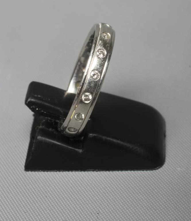 A PLATINUM ETERNITY RING with small diamonds in rub-over settings, London, 5.1g gross, size J 1/2 Image