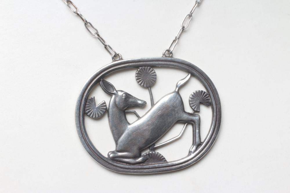 A GEORG JENSEN SILVER OVAL PENDANT designed by Arno Malinowski with a kneeling deer amongst flowers Image