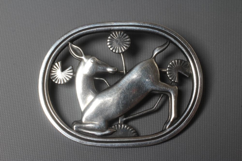 A GEORG JENSEN SILVER OVAL BROOCH designed by Arno Malinowski with a kneeling deer amongst flowers, Image