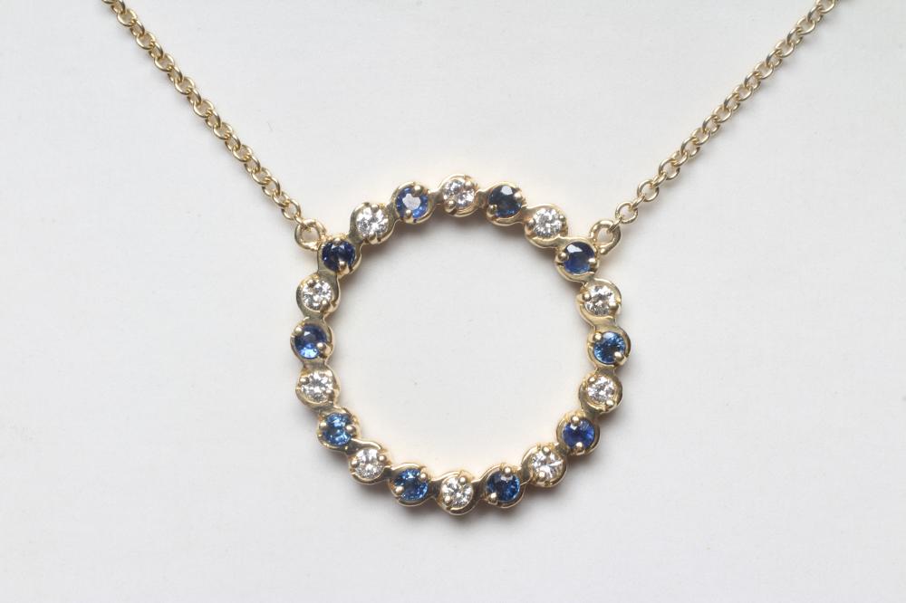 A SAPPHIRE AND DIAMOND OPEN CIRCLET PENDANT alternately set with ten facet cut sapphires and ten Image