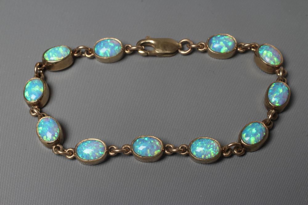 AN OPAL BRACELET, the eleven oval cabochon polished stones collet set in a 9ct gold frame with Image