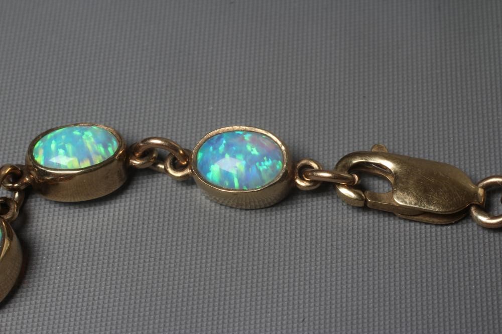 AN OPAL BRACELET, the eleven oval cabochon polished stones collet set in a 9ct gold frame with Image