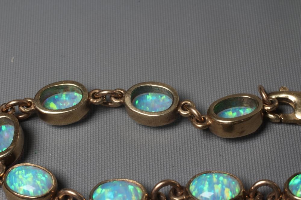 AN OPAL BRACELET, the eleven oval cabochon polished stones collet set in a 9ct gold frame with Image