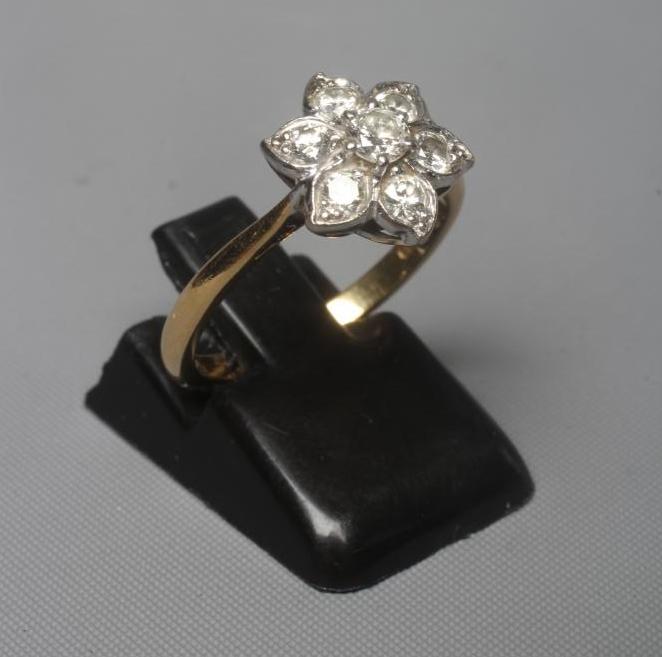 A SEVEN STONE DIAMOND CLUSTER RING, the old brilliant cut stones point set to a plain shank stamped Image