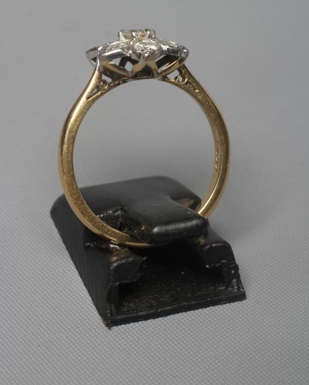 A SEVEN STONE DIAMOND CLUSTER RING, the old brilliant cut stones point set to a plain shank stamped Image