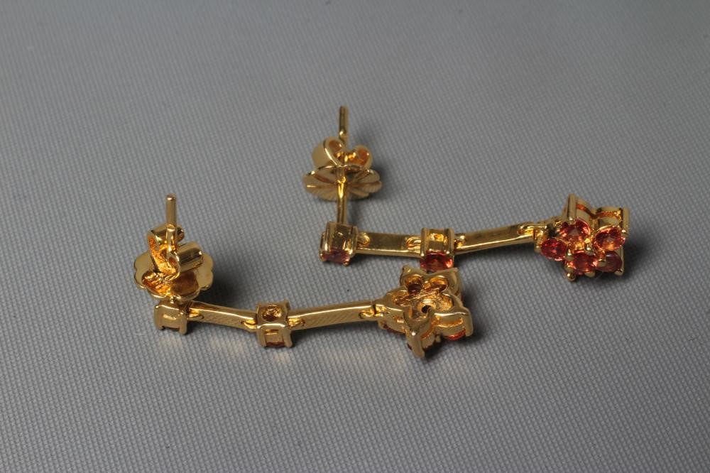 A PAIR OF ORANGE SAPPHIRE DROP EAR STUDS, the six stone cluster fixed to two knife edge bars with a Image