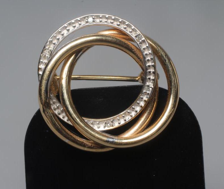A 9CT BI-COLOUR GOLD TRIPLE CIRCLET BROOCH, the white gold circle pave set with five small brilliant Image