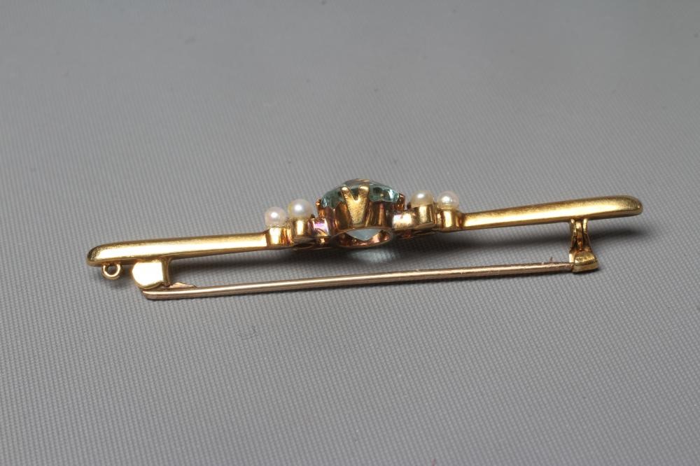 A LATE VICTORIAN PROPELLOR BAR BROOCH centred by an oval facet cut aquamarine flanked by a trefoil Image