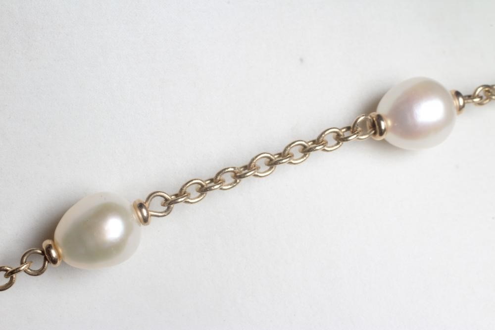 A 9CT GOLD CHAIN NECKLACE with thirteen oval cultured pearl spacers, the spring ring clasp with Image