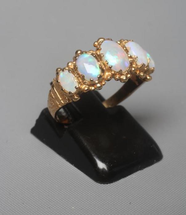A FIVE STONE OPAL RING, the oval cabochon polished graduating stones claw set to scroll carved Image