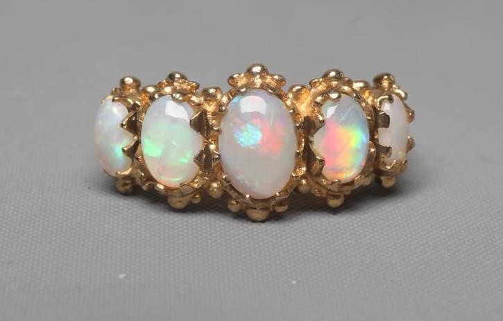 A FIVE STONE OPAL RING, the oval cabochon polished graduating stones claw set to scroll carved Image