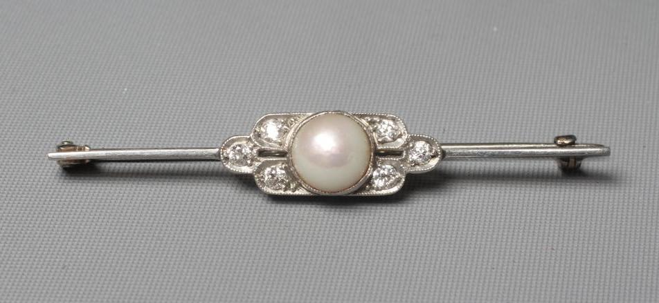 AN ART DECO DIAMOND AND PEARL BROOCH, the central pearl flanked by two triple diamond pave set Image