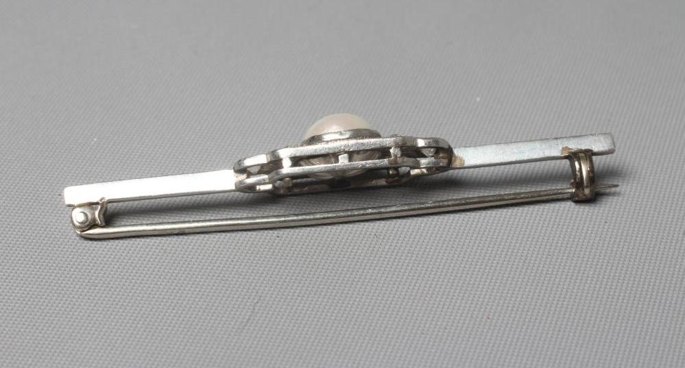 AN ART DECO DIAMOND AND PEARL BROOCH, the central pearl flanked by two triple diamond pave set Image