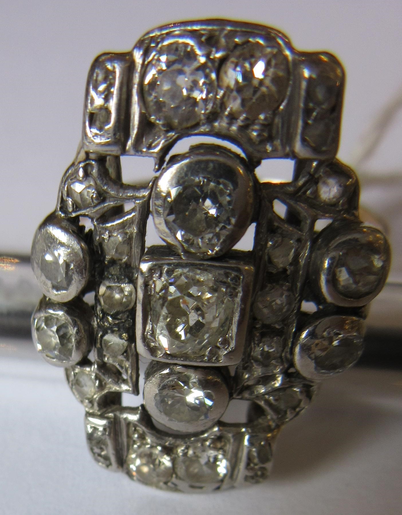 AN ART DECO PLAQUE RING, the numerous mix cut stones in rub-over and claw settings to a plain 18ct Image