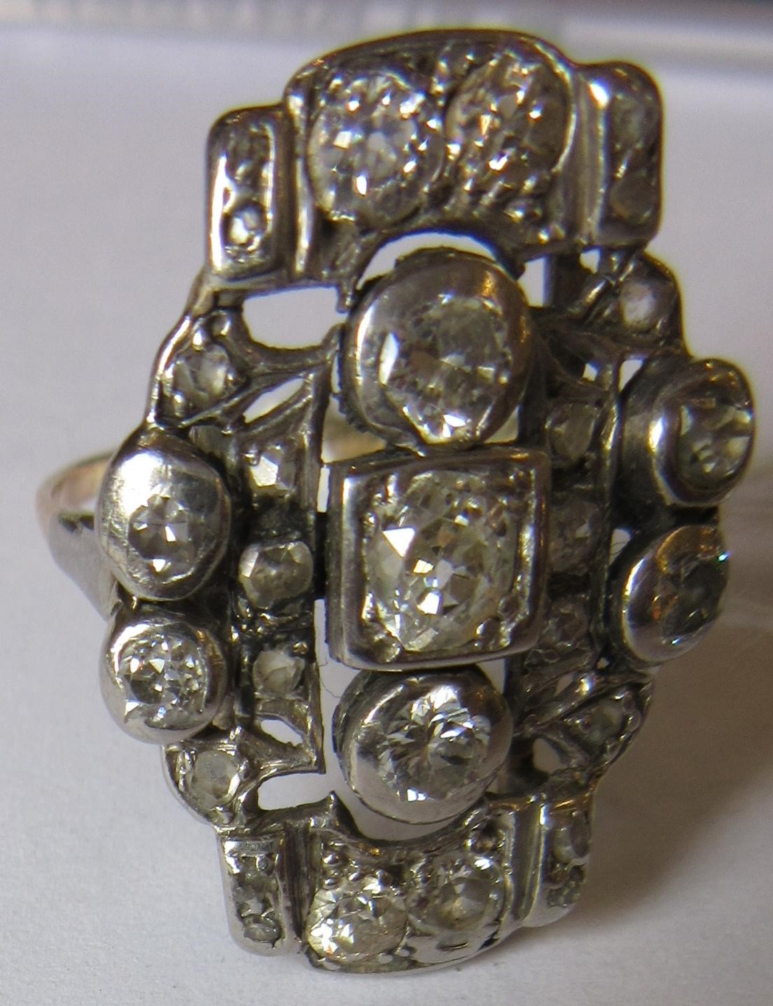 AN ART DECO PLAQUE RING, the numerous mix cut stones in rub-over and claw settings to a plain 18ct Image