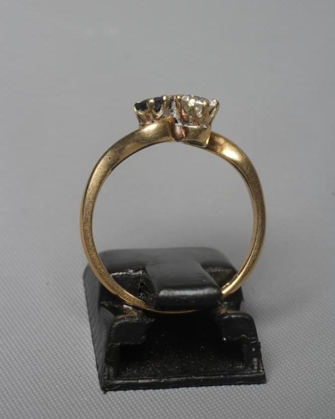 A TWO STONE SAPPHIRE AND DIAMOND CROSSOVER RING, the two facet cut stones claw set to a plain shank Image