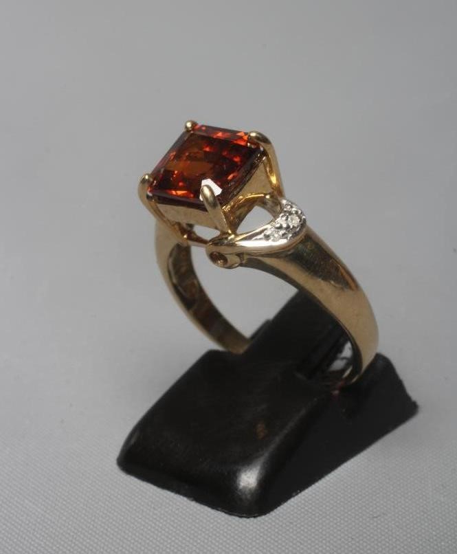 A GARNET DRESS RING, the square facet cut stone claw set to diamond point set open shoulders and a Image