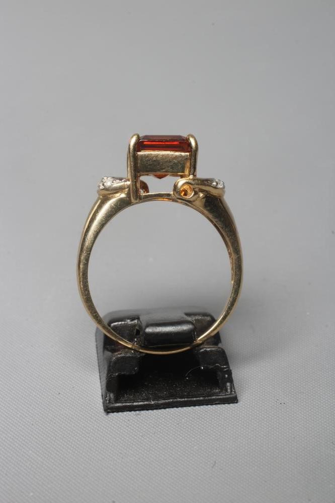 A GARNET DRESS RING, the square facet cut stone claw set to diamond point set open shoulders and a Image