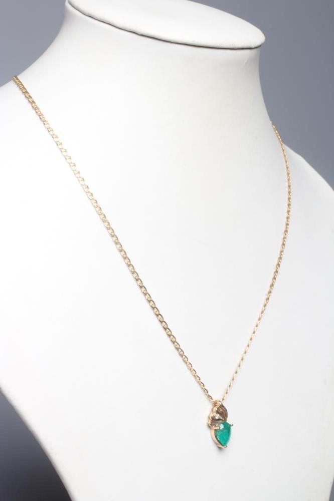 AN EMERALD PENDANT, the triangular facet cut stone claw set to an open scroll bale claw set with a Image