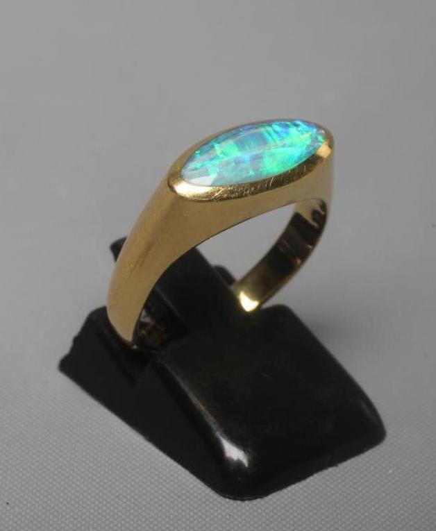 A BLACK OPAL RING, the eliptical polished stone in a rub-over setting to a plain 18ct gold shank, Image