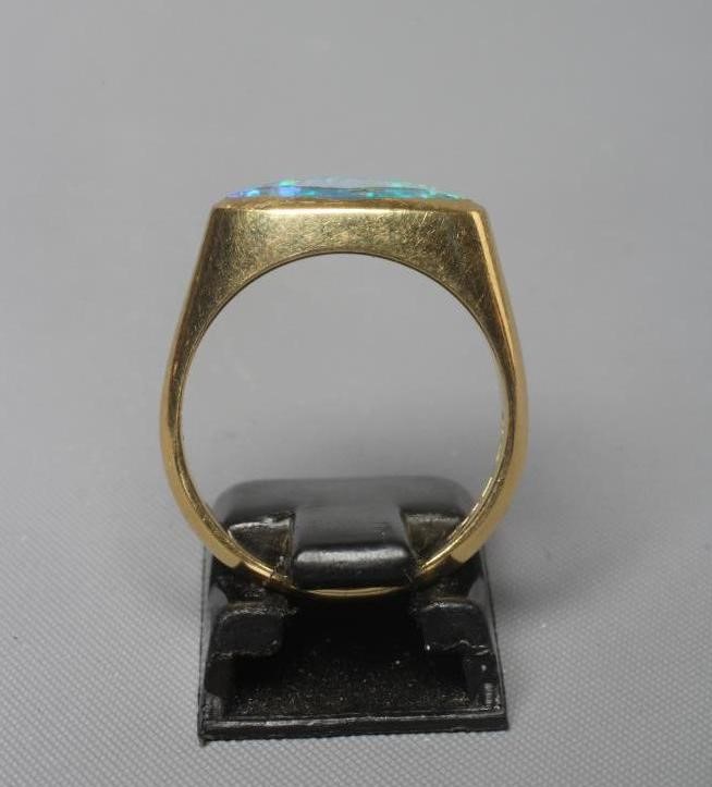 A BLACK OPAL RING, the eliptical polished stone in a rub-over setting to a plain 18ct gold shank, Image