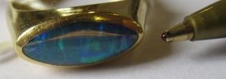A BLACK OPAL RING, the eliptical polished stone in a rub-over setting to a plain 18ct gold shank, Image