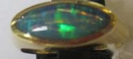 A BLACK OPAL RING, the eliptical polished stone in a rub-over setting to a plain 18ct gold shank, Image