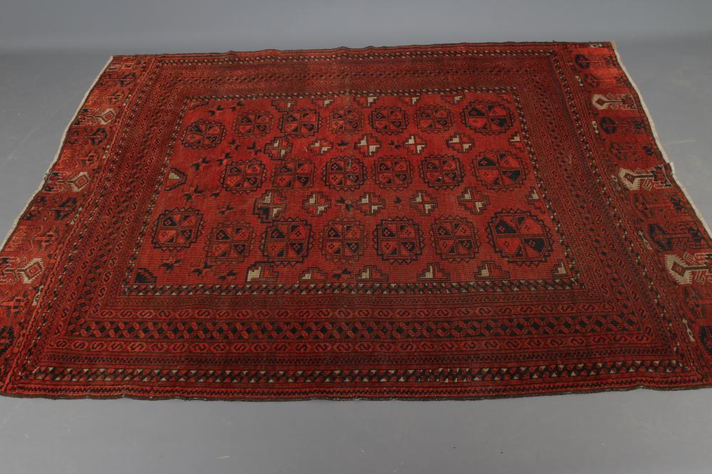 AN AFGHAN RUG, mid 20th century, the madder field with repeating gul pattern in indigo and ivory, Image