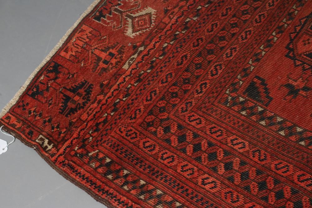 AN AFGHAN RUG, mid 20th century, the madder field with repeating gul pattern in indigo and ivory, Image