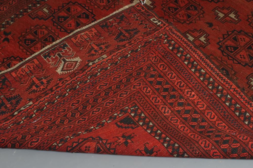 AN AFGHAN RUG, mid 20th century, the madder field with repeating gul pattern in indigo and ivory, Image