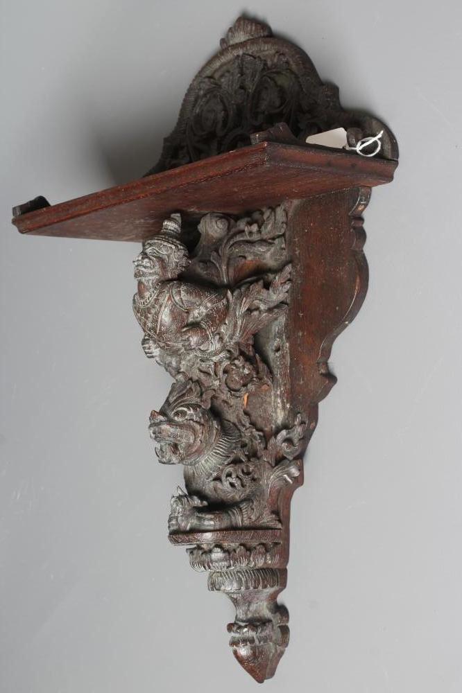 AN EASTERN HARDWOOD APPLIQUE intricately carved with a half length grimacing male figure over a Image